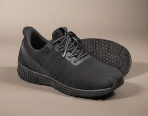 Pair of black athletic sneakers with textured uppers and thick soles on a beige background.