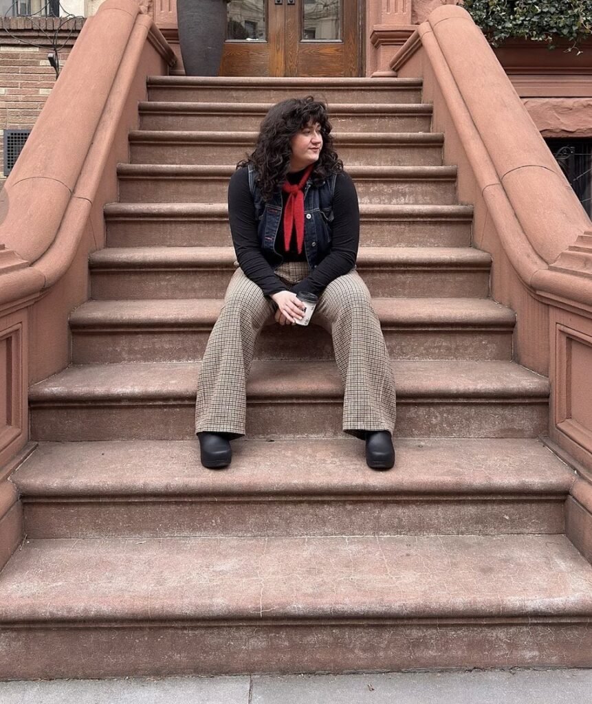 Person wearing black Danako clogs while sitting on stone steps.