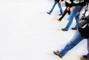 Action shot of several people walking confidently in supportive sneakers on a bright, clean surface.